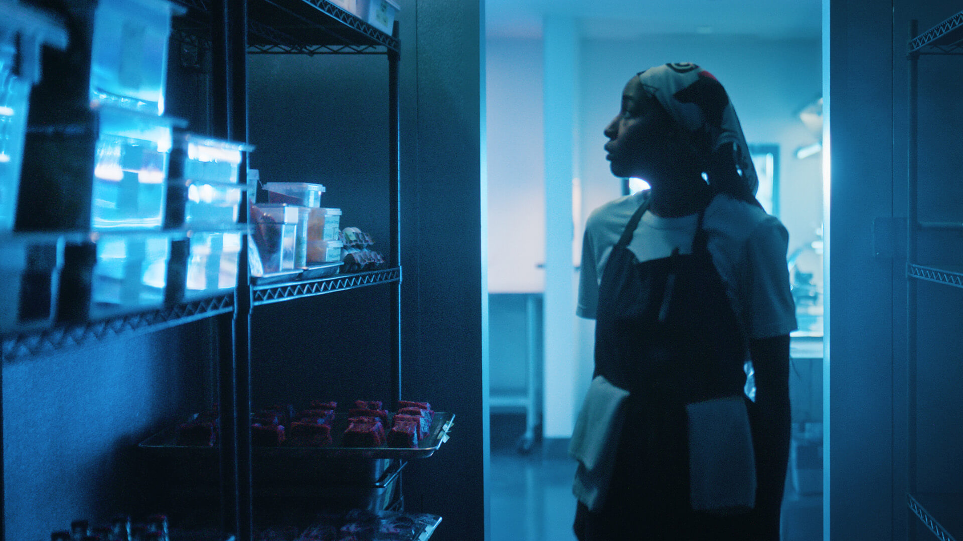 Sydney standing in the walk-in fridge looking at the bare shelves in The Bear.