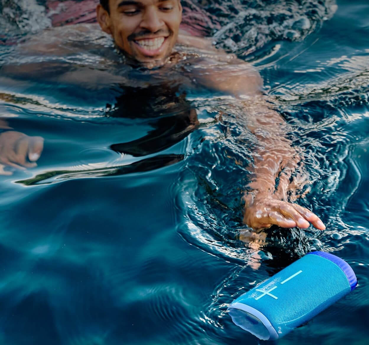 A man swimming with the Ultimate Ears Everboom portable Bluetoooth speaker.
