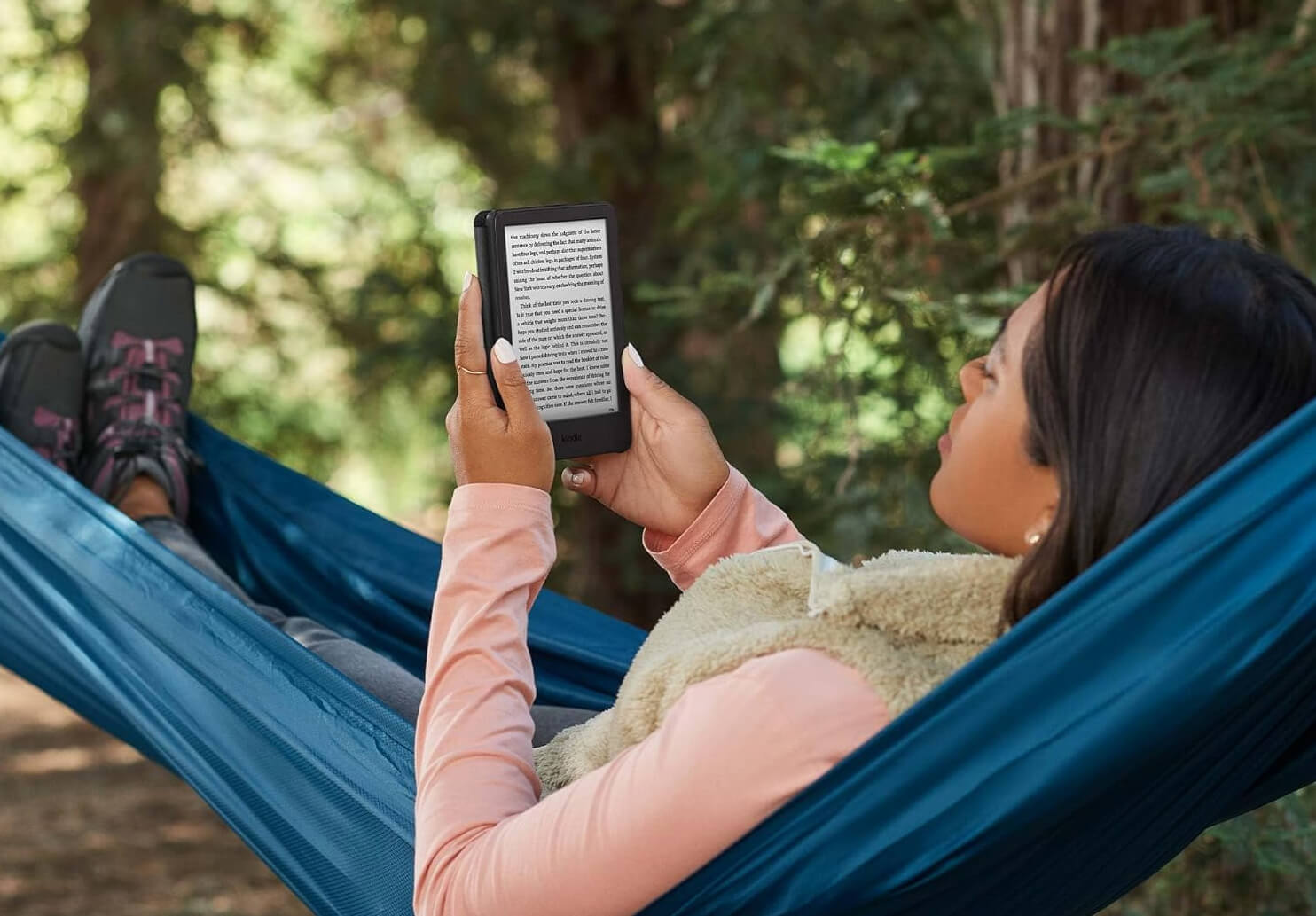 A girl in a hammock reading a book on an Amazon Kindle.