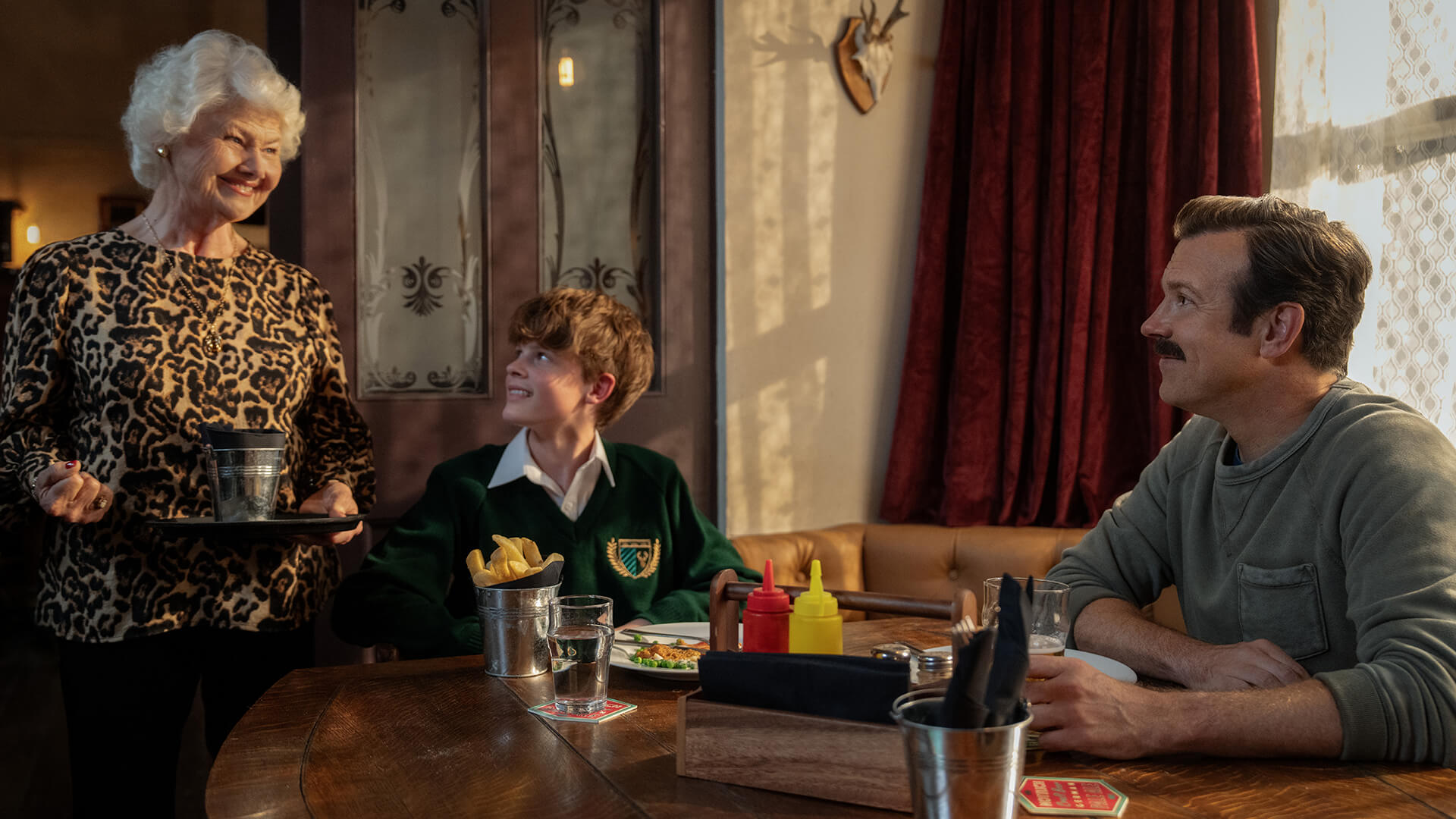 Mae talking to Henry and Ted in her pub in Ted Lasso.
