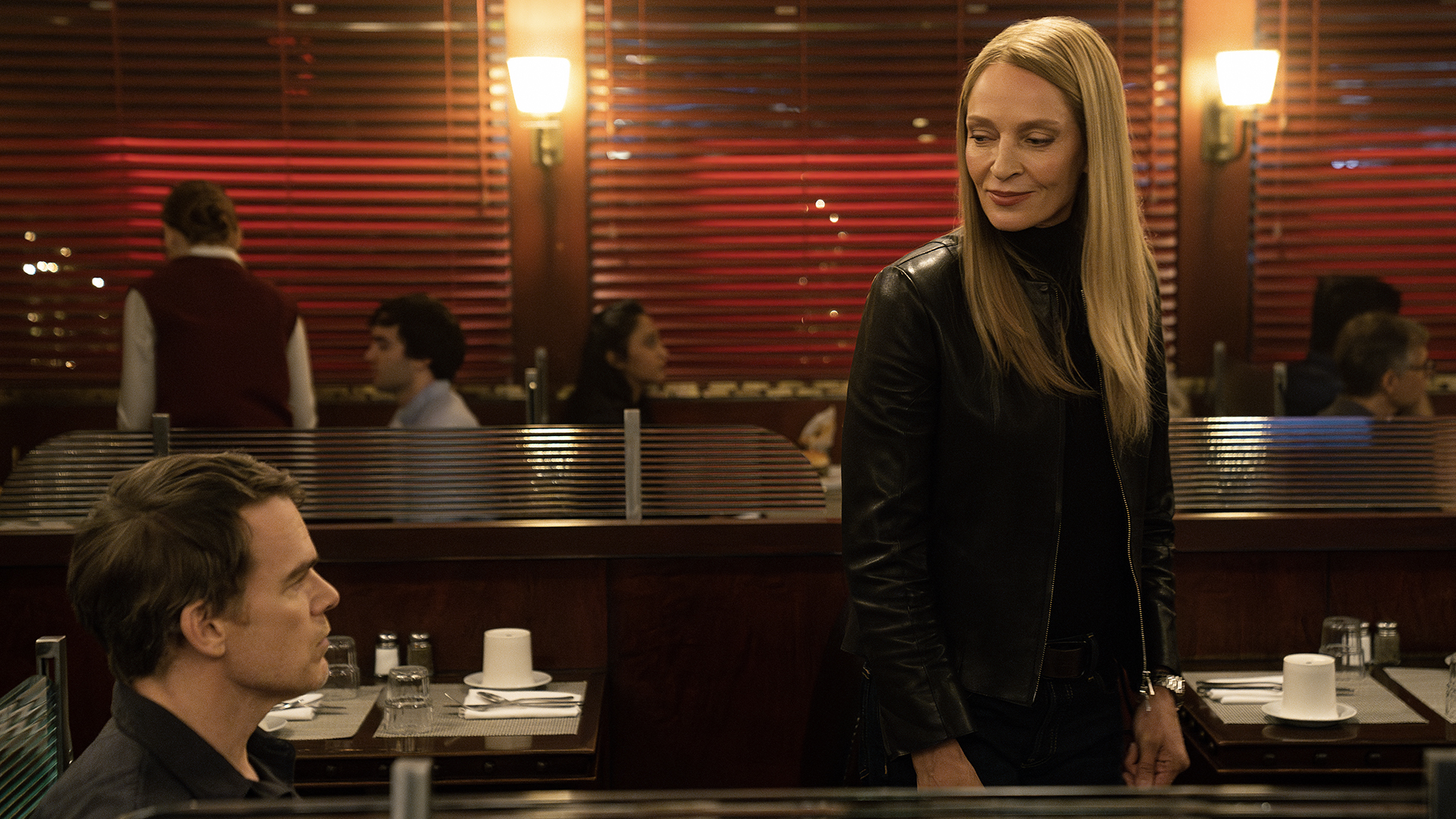 Dexter sitting in a restaurant talking to Charley walking by in Dexter: Resurrection.